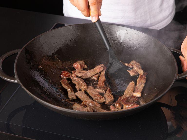 Einen Wok auf hoher Stufe erhitzen. Das Pflanzenöl dazugeben, wenn der Wok anfängt zu rauchen. Sobald das Öl warm ist, aber nicht raucht (ca. 60-70°C), das Rindfleisch dazugeben. Unter ständigem Rühren braten, bis das Rindfleisch fast gar ist. Das Rindfleisch aus dem Wok nehmen und zur Seite stellen.