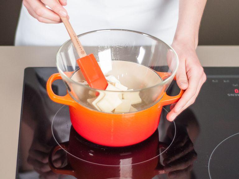To set up a double boiler, add some water to a large saucepan and bring to a simmer. Place a heat-resistant bowl on top of the saucepan. Add white chocolate to the bowl, allow to melt, and then set aside.