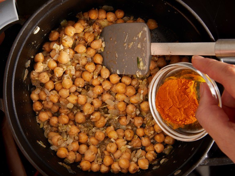 Add vegetable oil (or coconut oil) to a medium-sized heavy-based pot over medium high-heat. Once hot, add the onion, garlic, ginger and a pinch of salt and saute until soft, approx. 5 min. Next, add the chickpeas, and the ground turmeric, garam masala, sliced green chilli, and a decent grinding of black pepper. Fry for approx. 3 min, until fragrant.