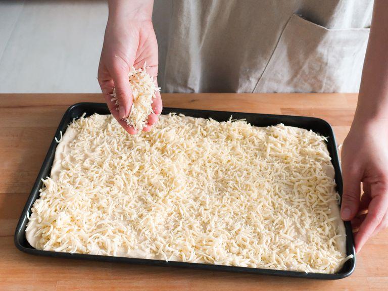Den Ofen auf 240°C vorheizen oder die Pizza-Einstellung deines Ofens verwenden. Ein Backblech großzügig einölen. Jetzt den Pizzateig auf das Backblech geben und vorsichtig in alle Ecken drücken, bis das Blech komplett ausgefüllt ist. Eine großzügige Schicht geriebenen Mozzarellakäse über die gesamte Teigfläche streuen.