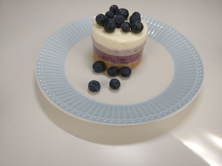 Repeat this process for the remaining light violet-colored mixture and the white mixture. Allow each layer to cool well, and transfer the cheesecakes to the fridge overnight. To serve, gently remove the dessert rings and decorate with fresh blueberries. Enjoy!