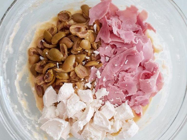 Slice the olives, and cut the ham in small pieces. Chop or grate the cheese : here I used goat's cheese, but usually it is made with Gruyère or Emmental. Incorporate to the batter.