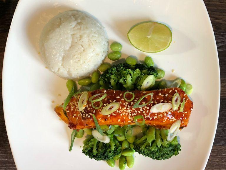 Plate up the rice, broccoli and edamame beans. Remove the salmon from the oven and gently place on the broccoli. Sprinkle the sesame seeds and sliced spring onion over the salmon. Divide the remaining lime in two and add to plate.