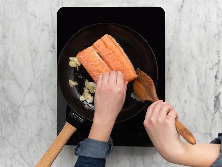 Heat vegetable oil in a frying pan over medium-high heat. Add salmon fillet skin-side down and fry for approx. 3 min., or until the skin is crispy. Add sliced ginger and garlic, then flip the salmon, reduce heat to medium-low, and let the salmon fillet cook to desired level of doneness.