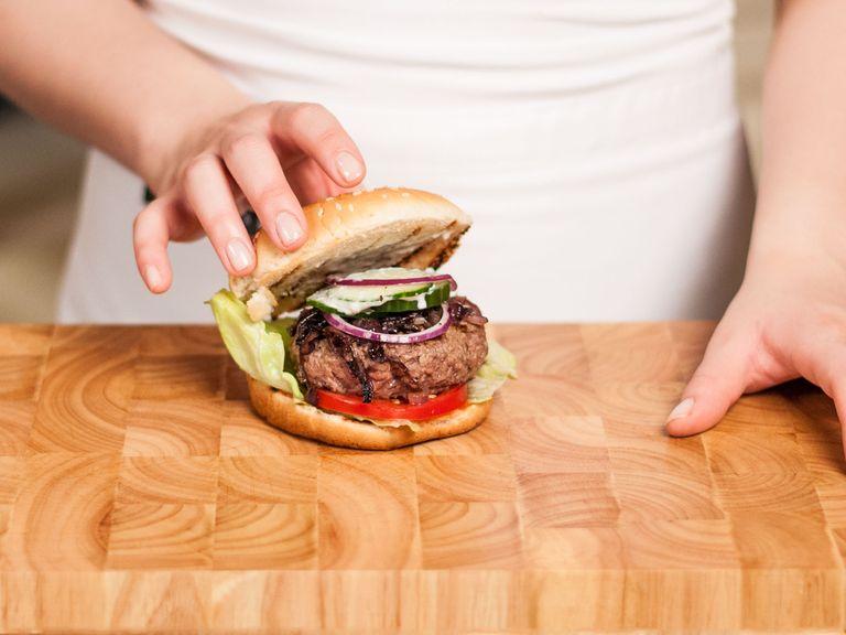 Assemble burger with grilled patties, tomato and cucumber slices, raw onion slices, sautéed onions, iceberg lettuce, ketchup, and mayonnaise. Enjoy!