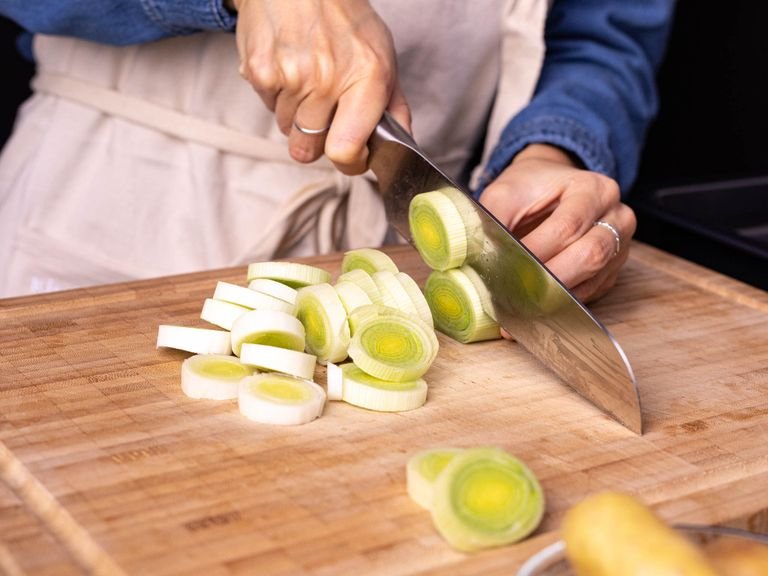 Backofen auf 230°C vorheizen. Falls gewünscht, Hähnchenschenkel in Ober- und Unterschenkel zerlegen. Zitrone in dünne Scheiben und Kerne entfernen. Lauch in dünne Scheiben schneiden und in eine Schüssel mit Wasser geben, um Dreck oder Sand zu entfernen, danach abgießen. Kartoffeln vierteln und auf ein Backblech geben. Den abgegossenen Lauch, einen Teil der Kapern, Olivenöl, Salz und Pfeffer auf das Backblech geben und vermengen.
