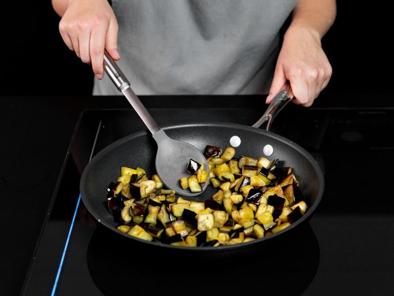 Olivenöl in einer Pfanne über mittlerer Hitze erwärmen. Aubergine darin ca. 6 - 8 Min. anbraten, bis sie gut gebräunt ist. Anschließend aus der Pfanne nehmen.