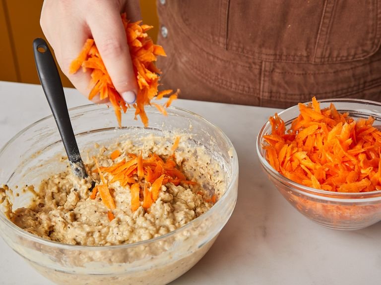In a large bowl, mix flour, oats, spices, baking powder, baking soda, and salt. Mix dry ingredients into wet ingredients just until combined, then fold in the grated carrots and half of the walnuts.