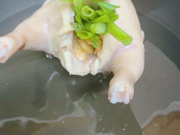 Blanch the chicken to get rid of the blood. You can add some cooking wine. While waiting, julienne the scallions and slice the ginger. Once the chicken is cleaned, give it a short message with the salt-just a little bit is enough. Then... emmm... stuff the chicken with as much ginger and scallion as possible as the picture shows.