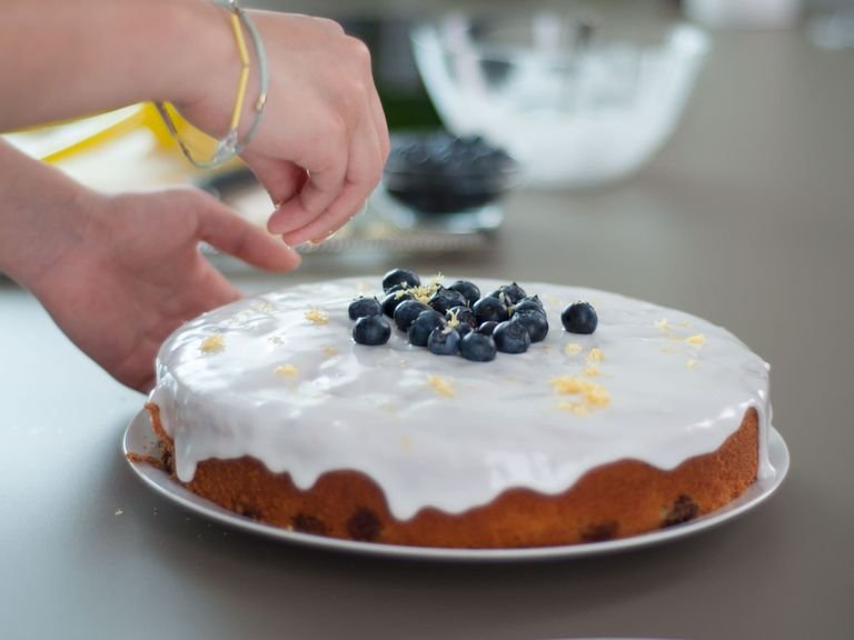 For the icing, whisk together confectioner’s sugar and juice from the remaining lemon. Evenly spread over cake. Garnish with the remaining blueberries and remaining lemon zest.