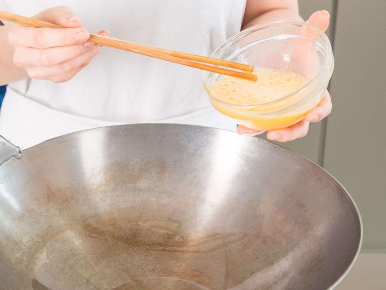 Etwas Pflanzenöl in einen Wok über mittlerer Hitze geben und Eier darin verrühren und braten.