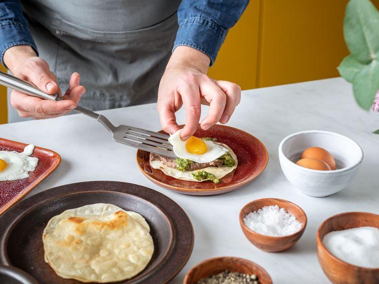 To assemble the huevos rancheros top each tortilla with a fried egg and spoon plenty of salsa verde over the top. Garnish with cilantro and serve with a scoop of refried beans. Enjoy!