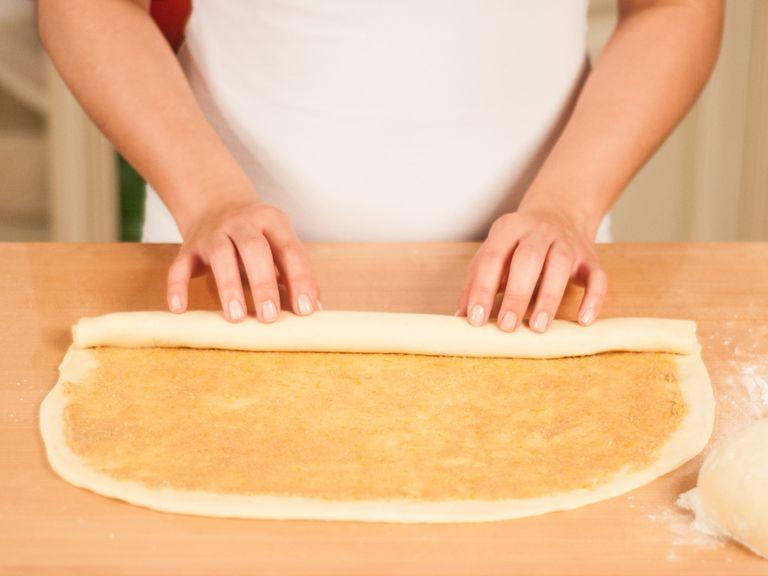 Starting at the long end, roll up the dough.