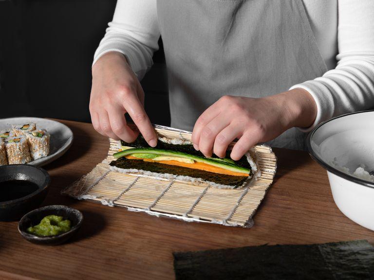 Roll together tightly by lifting the front side of the sushi mat and rolling it backwards.