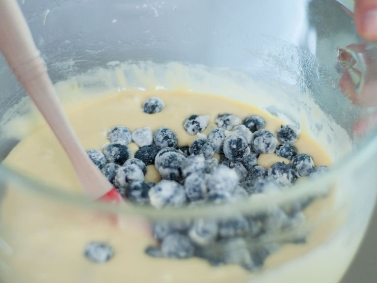 Set aside some of the blueberries for garnish. Use a little bit of flour to coat blueberries. Now add flour, baking powder, and coated blueberries to dough. Beat until ingredients are well incorporated.