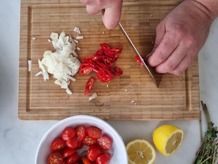 Peel the asparagus and cut into slices. Finely dice the onion and garlic. Then finely slice the chili peppers and halve the cherry tomatoes. Finally, cut the lemon in half.