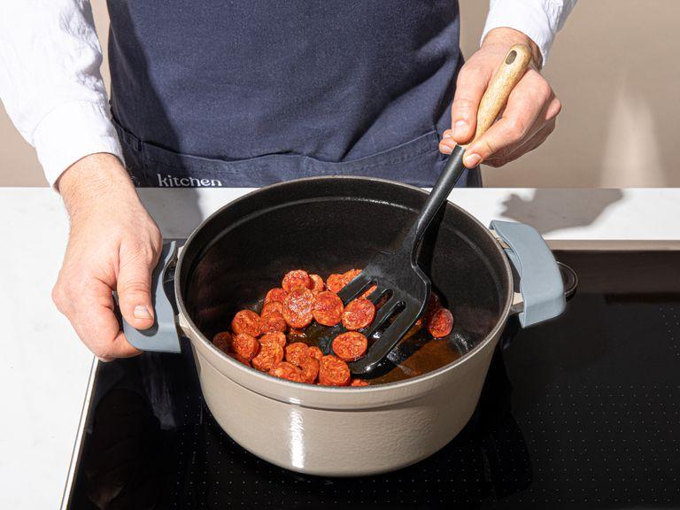 Öl in einer großen Pfanne erhitzen. Hähnchen von allen Seiten goldbraun anbraten, dann die Chorizo für ca. 2 Min. hinzugeben. Herausnehmen und beiseitestellen.