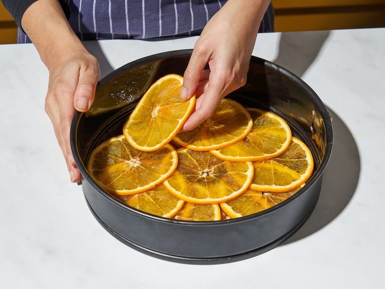 In a bowl add some sugar and the red wine and whisk to combine. Pour into the bottom of the prepared pan and tilt in all directions to spread evenly across the bottom. Arrange the orange slices in an overlapping pattern across the bottom of the pan and set aside; if you have extra orange slices, eat or make some orange-scented “spa water” by transferring them to a large jug of water.