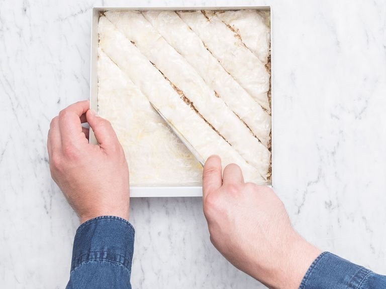 Using a sharp knife, score the baklava into the desired pattern, making sure you cut all the way through so the syrup can soak through. Transfer to the oven and bake at 200°C/390°F for approx. 20 min. or until golden brown on top.
