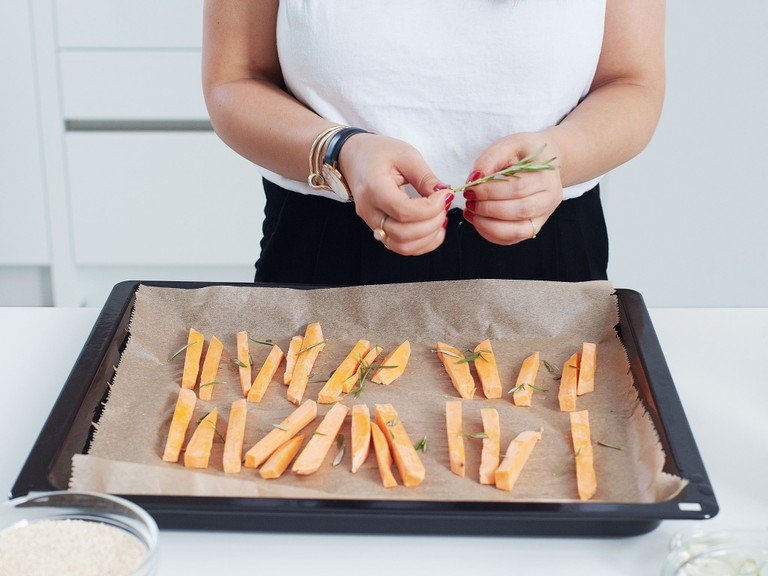 Preheat oven to 200°C/400°F. Peel sweet potato and cut into sticks. Chop rosemary. Transfer potatoes to a parchment-lined baking tray. Season with salt, top with rosemary, and drizzle with olive oil. Bake for approx. 30 min.