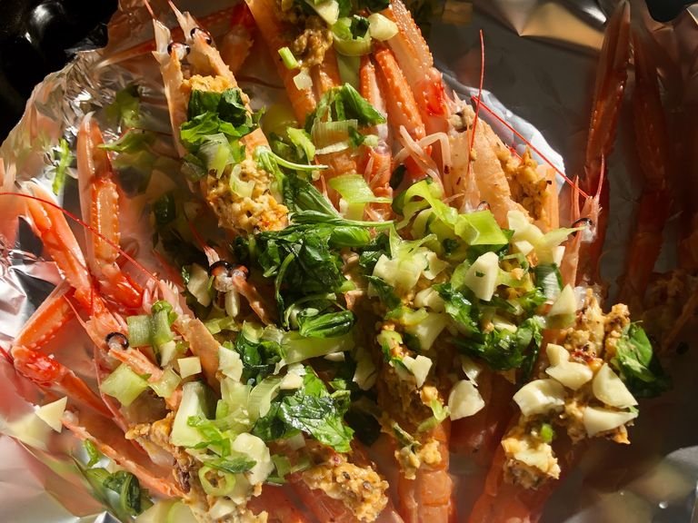 Clean the Langoustines by using knife to cut open the back and then stuff the garlic and black pepper cream/butter inside the back of Langoustines. Then put spring onions on top of the Langoustines