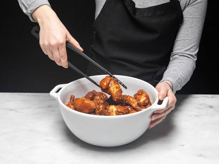 Die fertigen Chicken Wings in eine große Schüssel geben, mit der heißen Sauce übergießen und verrühren. Auf einem Teller servieren und mit Frühlingszwiebeln, Chilis und Sesam bestreuen. Guten Appetit!