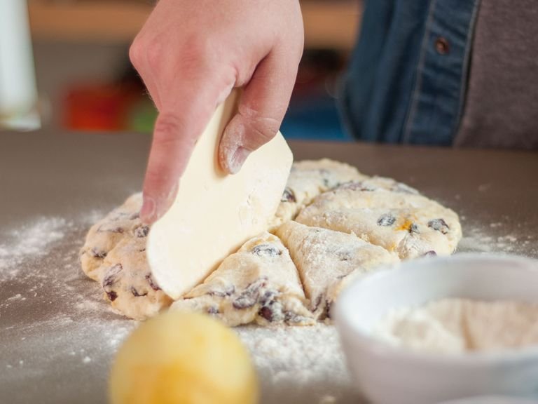 Transfer dough to floured work surface, spread out two fingers thick, and cut into triangular slices. Place each scone on a lined baking sheet and bake in preheated oven at 200°C/400°F for approx. 18 – 20 min. or until they are golden brown.