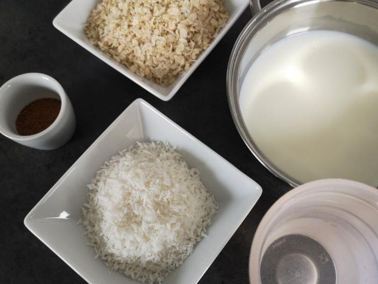 Reisflocken, Kokosraspel und Kokosblütenzucker mit der Milch und dem Wasser unter ständigem Rühren köcheln lassen.