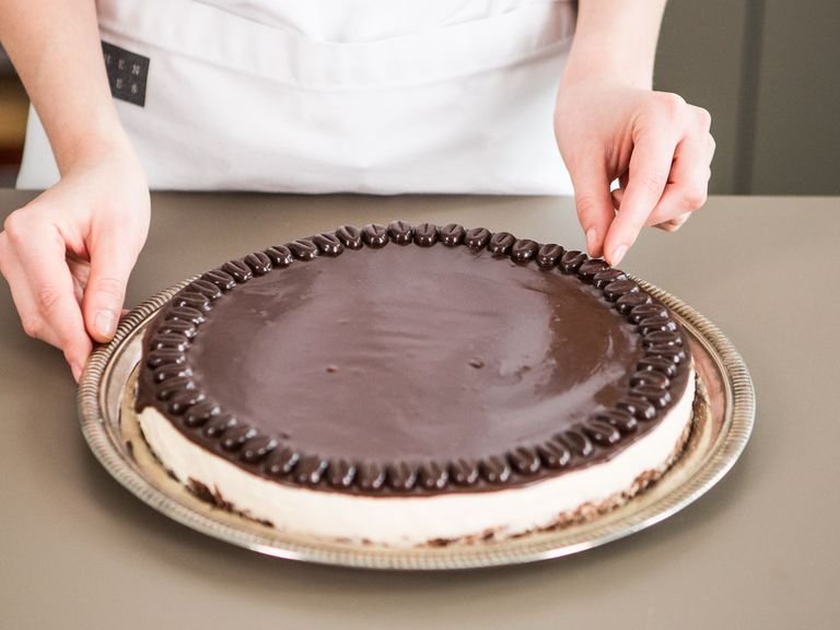 Carefully run knife around edges of the baking form. Remove cake and transfer to a cake platter. Evenly spread ganache over top of cheesecake. Garnish cake with an outer ring of coffee flavored chocolates. Enjoy with a cold glass of Baileys!