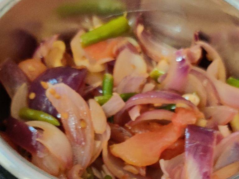 Add 2 tbsp oil in kadai on medium flame and add black cardamom. After 1 minute add onions, tomatoes, green chillies, garlic cloves and cashew nuts. Fry for 5-7 minutes. Allow to cool and make a paste.