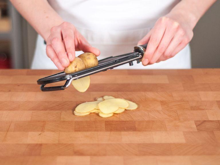 Kartoffeln mit Gemüsehobel oder scharfem Messer in dünne Scheiben schneiden.