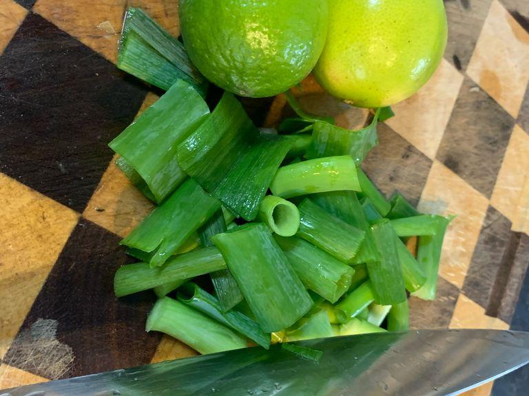Cut spring onion and add to the dish. Cut lime in half and add the juice to the dish.