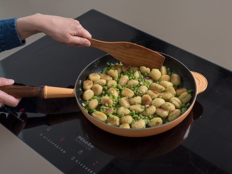 Add chopped garlic to gnocchi in the frying pan and sauté for approx. 2 min. Add the chicken broth and the mashed peas, mix well, and leave to simmer for approx. 3 min.