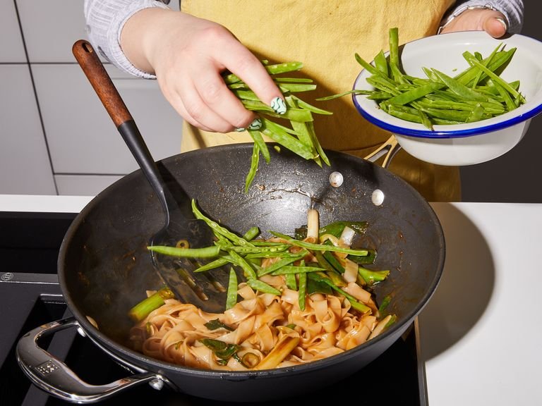 Add toasted sesame oil to a wok or large frying pan and heat over medium high. Add scallion and stir fry until charred, approx 5 min. Then add rice noodles and sauce and stir fry for 4 min. Add snap peas and green chilli and toss for 1 min. Serve noodles with grapefruit segments, fried wild rice, and garnish with mint. Enjoy!