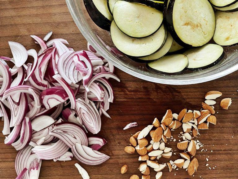 Wash the eggplant and cut into thin slices. Mix in a bowl with 1 tsp salt and let sit. Peel the onion and cut into fine slices. Remove the pomegranate seeds from the skin and roughly chop the almonds.