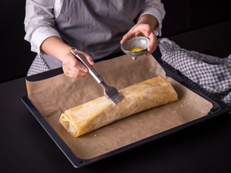 Den Strudel vorsichtig auf ein mit Backpapier ausgelegtes Backblech geben und mit restlicher Butter bestreichen. Für ca. 35 – 40 Min. bei 180ºC goldbraun backen.