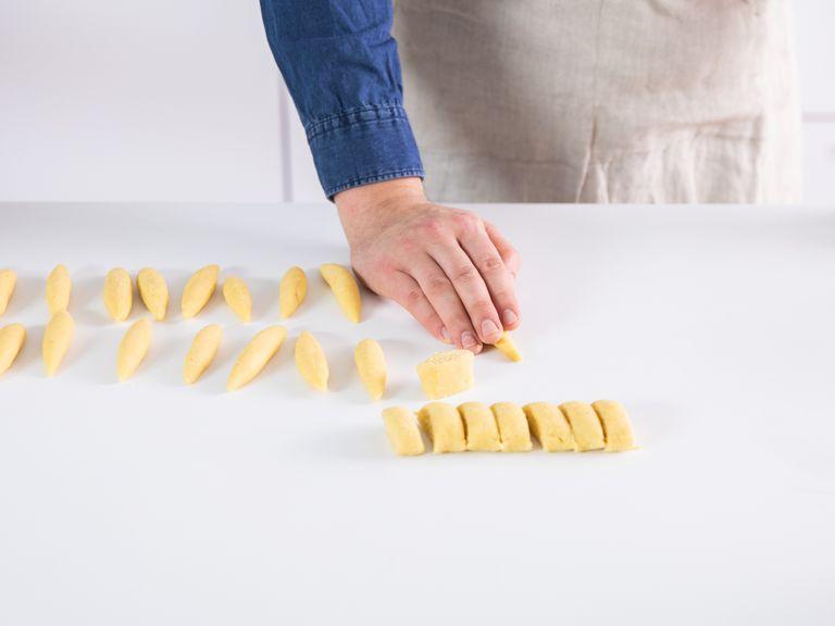Halve the dough and roll into logs, approx. 2-cm/3/4-in. in diameter. Slice each log into approx. 2-cm/3/4-in. thick pieces. Use your hands to roll each piece into a finger shaped dumpling with a thick middle and tapered ends.