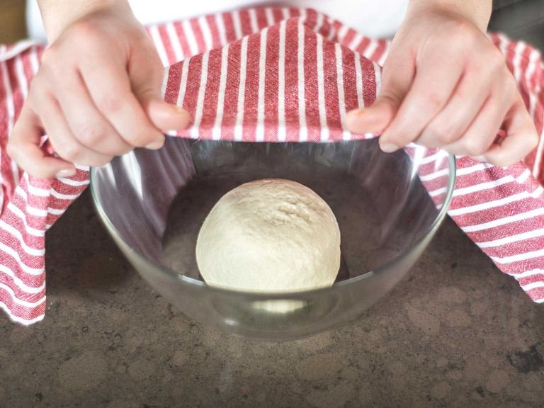 Now, place the dough in a bowl, cover with a kitchen towel, and leave it to rest in a warm place for approx. 25 – 30 min.