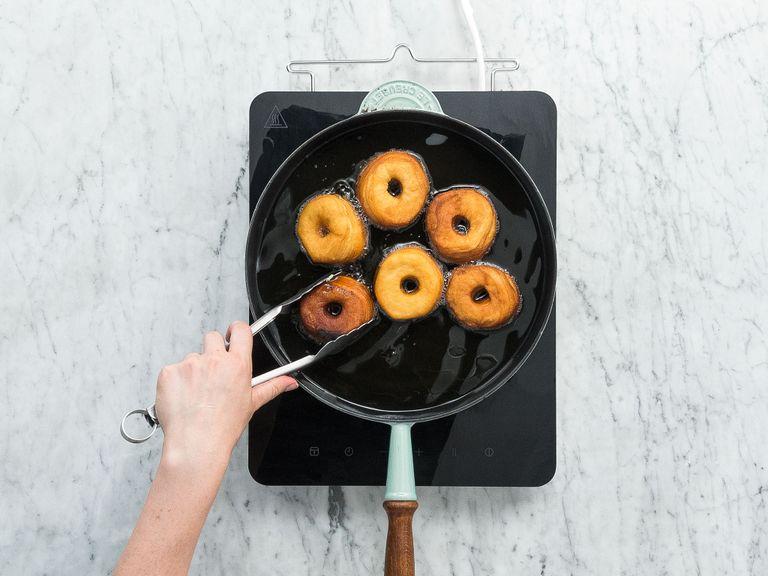 Form the dough into 12 rounds and cut out a hole in the center of each one to make doughnuts. In a deep frying pan, heat the oil to approx. 180°C/356°F. Fry the doughnuts until golden brown on both sides for approx. 2-3 min. Transfer the doughnuts to a paper towel-lined plate to drain.