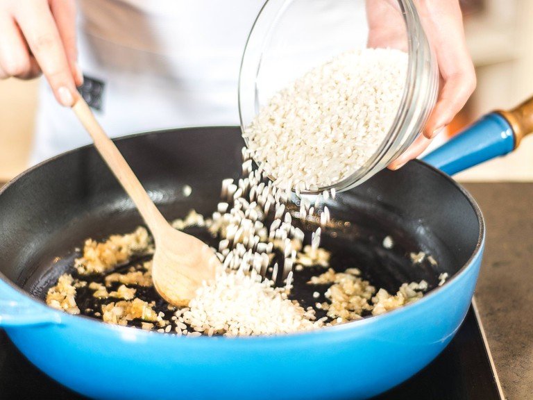 Zwiebeln und Knoblauch mit etwas Pflanzenöl anschwitzen. Nun den Risotto-Reis hinzugeben und mit anschwitzen bis das Korn leicht glasig wird.