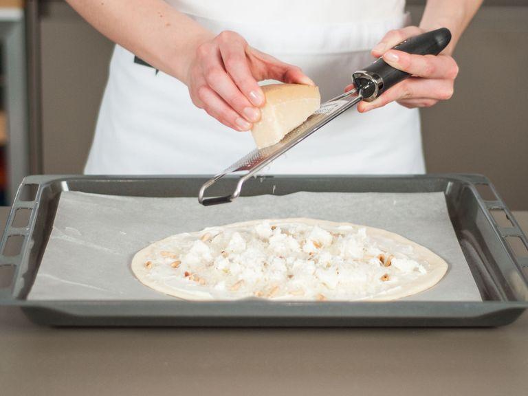 Place dough on a lined baking tray. Spread crème fraîche evenly over dough. Sprinkle with pine nuts, feta, and onions. Grate Parmesan on top with a fine grater. Place in the oven and bake at 220°C/425°F for approx. 10 - 15 min.