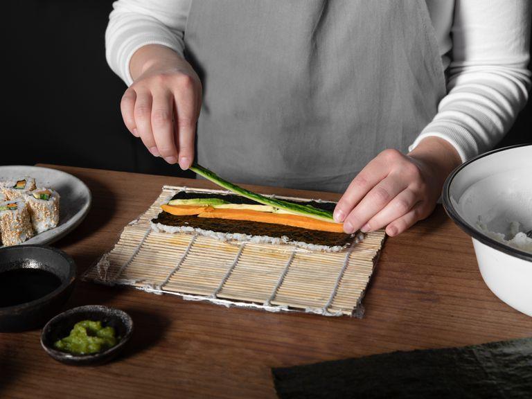 Flip the whole seaweed sheet so the rice is underneath. Spread wasabi paste down the middle of the sheet. Fill with avocado and sweet potato for a vegetarian roll, or salmon and cucumber.