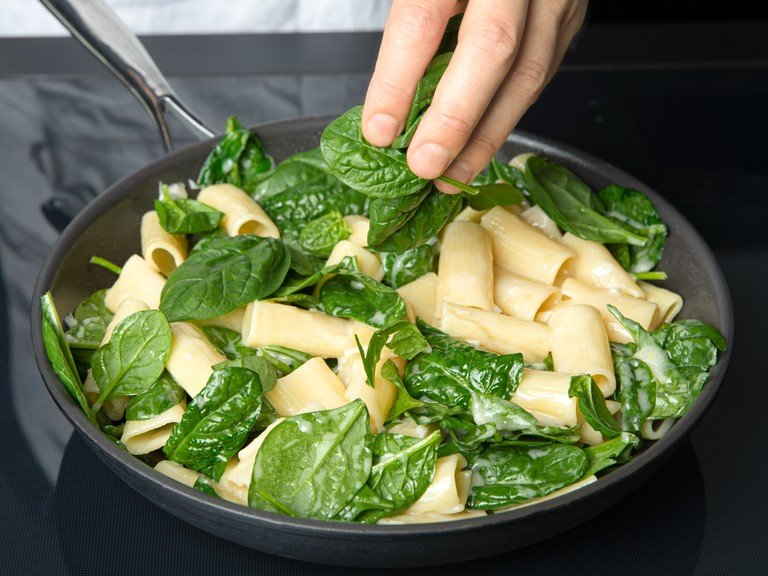 Add baby spinach to the pasta, mix, and let it wilt. Season pasta with a little salt and lemon zest. Then season generously with pepper. Arrange pasta on deep plates, top with pistachios and shallots, and garnish with remaining lemon zest and parmesan. Serve immediately.