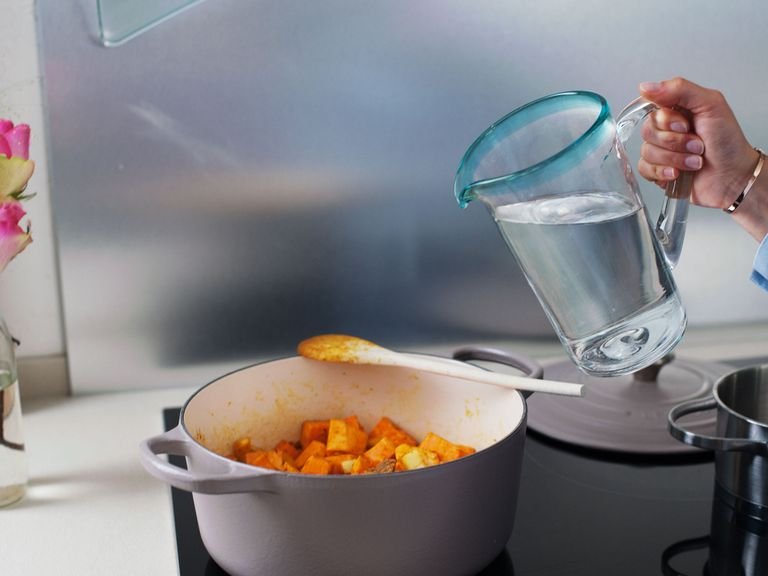 Wasser, Gemüsebrühe und Tomaten dazugeben, vermischen und aufkochen. Hitze reduzieren und für ca. 15 - 20 Min. köcheln lassen, bis die Süßkartoffeln weich, aber noch bissfest sind.