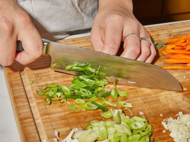 Peel ginger, then slice into very thin strips. Peel garlic and crush with the flat side of your knife. Peel and julienne carrots. Thinly slice scallions, reserving the green parts for serving.