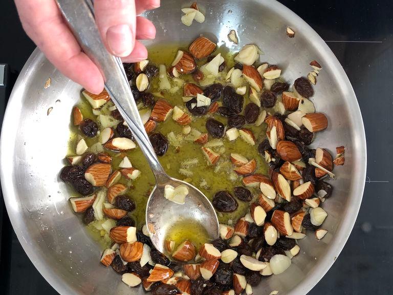 Für das crunchy Topping Olivenöl in einer Pfanne erhitzen, Mandeln hinzufügen und kurz frittieren. Dann Knoblauch und Rosinen hinzufügen und frittieren, bis alles knusprig braun ist. In eine Schüssel füllen und beiseite stellen.