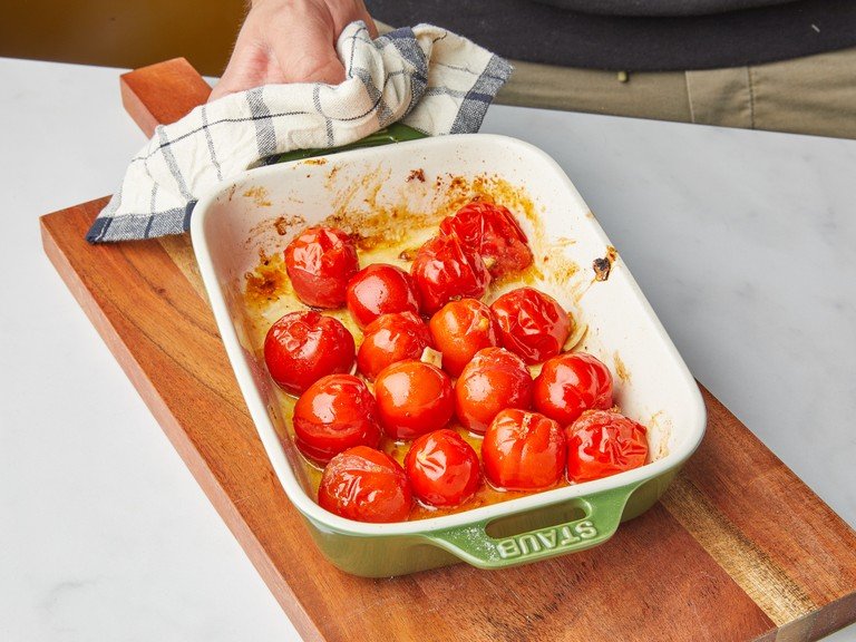 In der Zwischenzeit die Tomaten in einer Auflaufform mit Öl, Honig, Knoblauch, Salz, Pfeffer und Zitronenschale vermischen. Die Kirschtomaten auf der mittleren Schiene in den Ofen schieben und ca. 20 Min. rösten, bis sie reißen.
