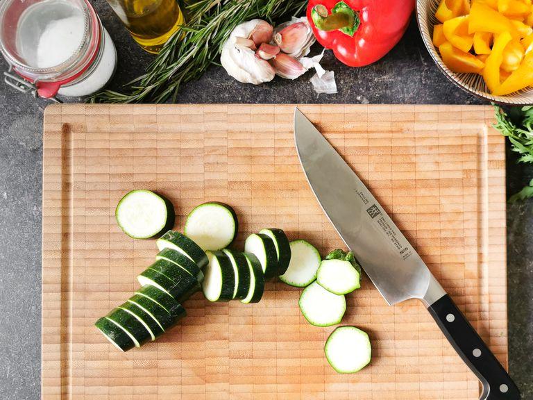 Slice bell peppers into thin strips. Cut zucchini into thick slices. Peel and roughly chop garlic. Pluck rosemary, then roughly chop the leaves.
