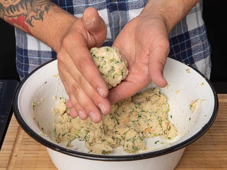 Use wet hands to shape the mixture into round equally sized bread dumplings. Transfer them to a baking tray, cover with plastic wrap, and set aside.
