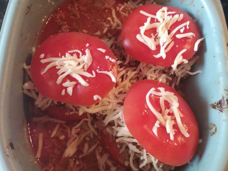 Tomaten mit Hack füllen und Brühe zugießen. Käse über die gefüllten Tomaten reiben und den Tomatendeckel wieder drauf legen. Falls du noch Hack übrig hast kannst du es mit in die Brühe geben.
